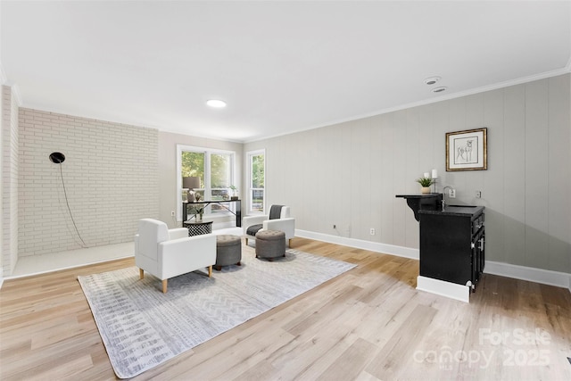 living room with sink, crown molding, brick wall, and light wood-type flooring