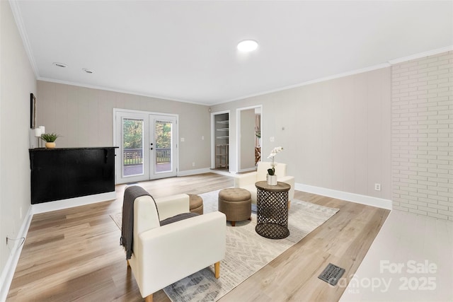 living room featuring ornamental molding, light wood-type flooring, and french doors