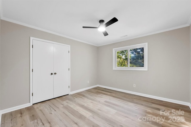 unfurnished bedroom featuring ceiling fan, ornamental molding, light hardwood / wood-style floors, and a closet