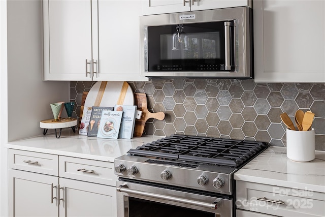 kitchen with appliances with stainless steel finishes, white cabinets, and backsplash