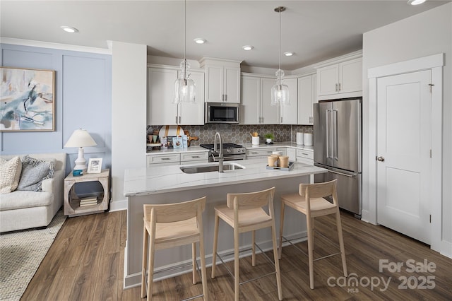 kitchen with backsplash, a breakfast bar, premium appliances, white cabinetry, and dark wood-style flooring