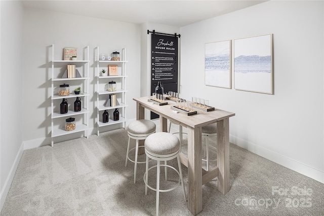 carpeted office space with a barn door and baseboards