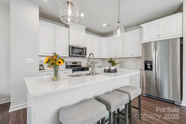 kitchen with a sink, stainless steel appliances, dark wood-type flooring, recessed lighting, and decorative backsplash