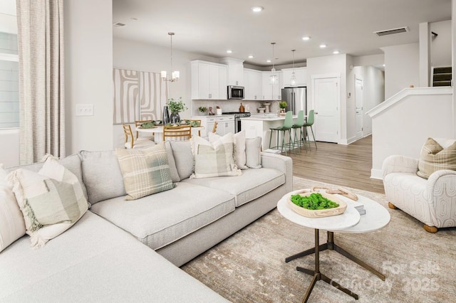 living room with a notable chandelier and light hardwood / wood-style floors