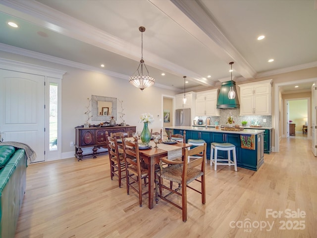 dining room with ornamental molding, sink, beam ceiling, and light hardwood / wood-style flooring