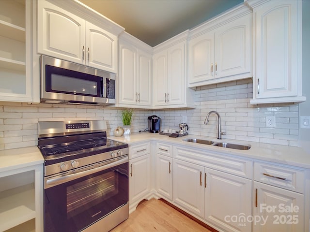 kitchen with stainless steel appliances, tasteful backsplash, sink, and white cabinets