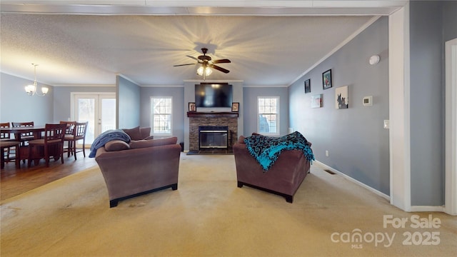 carpeted living room with ornamental molding, a fireplace, and ceiling fan with notable chandelier