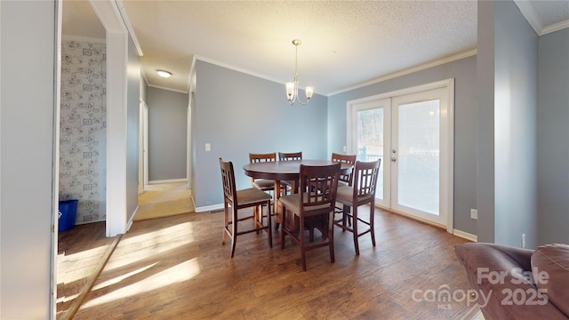 dining area with wood-type flooring, ornamental molding, a textured ceiling, french doors, and a chandelier