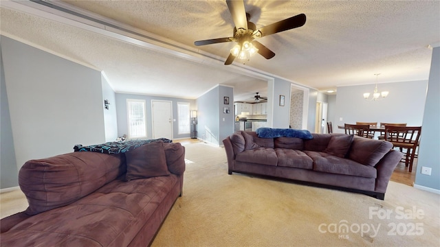 carpeted living room featuring ornamental molding, ceiling fan with notable chandelier, and a textured ceiling