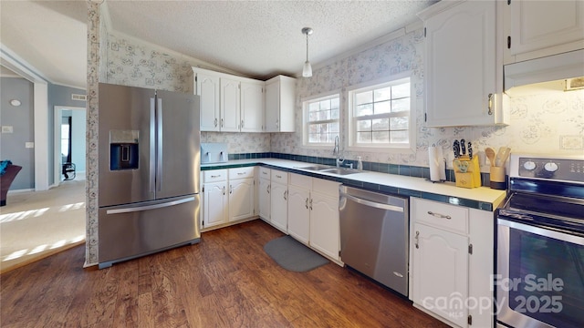 kitchen with dark hardwood / wood-style floors, sink, white cabinets, stainless steel appliances, and a textured ceiling