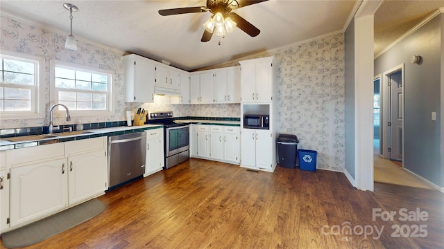 kitchen with sink, white cabinetry, appliances with stainless steel finishes, tile counters, and hardwood / wood-style floors