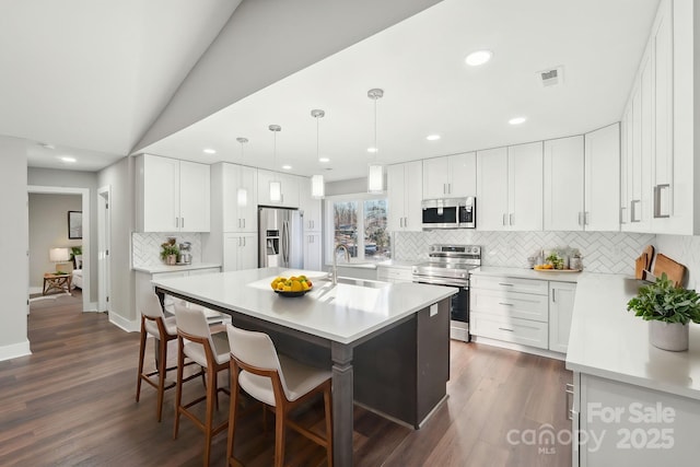 kitchen featuring white cabinetry, stainless steel appliances, and a kitchen island with sink