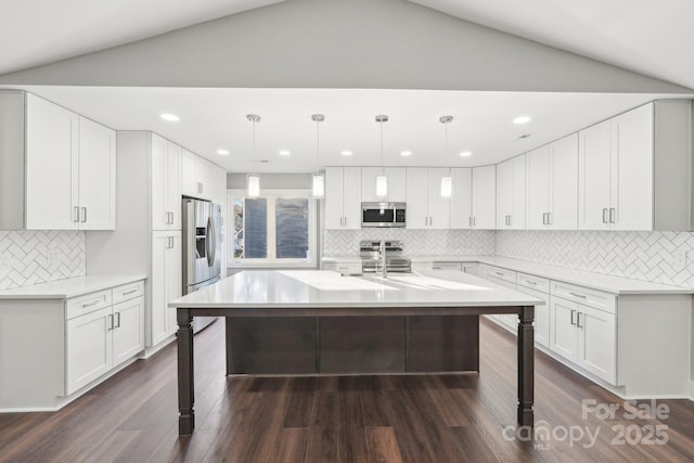 kitchen featuring stainless steel appliances, hanging light fixtures, and white cabinets