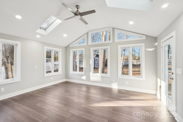 unfurnished sunroom featuring a healthy amount of sunlight, vaulted ceiling with skylight, and ceiling fan