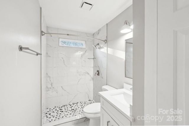 bathroom featuring vanity, tiled shower, and toilet