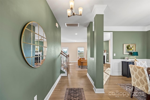 hall with ornamental molding, a chandelier, and light hardwood / wood-style floors