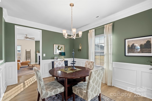 dining area with crown molding, ceiling fan with notable chandelier, and light hardwood / wood-style floors