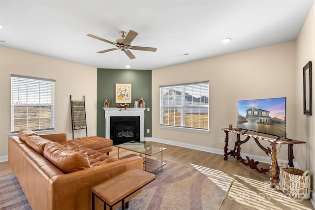 living room with ceiling fan, plenty of natural light, and light wood-type flooring