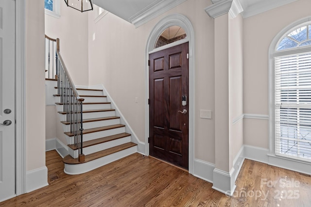 foyer with decorative columns, wood-type flooring, and crown molding