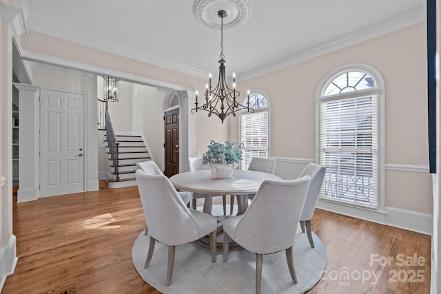 dining area featuring an inviting chandelier, crown molding, and light hardwood / wood-style floors