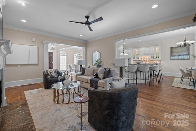 living room with ceiling fan with notable chandelier, ornamental molding, and dark hardwood / wood-style floors