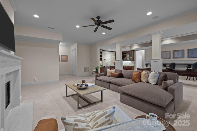 living room with light carpet, ornamental molding, ceiling fan, a high end fireplace, and decorative columns