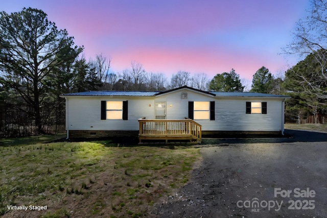 view of front of property with a deck and a lawn