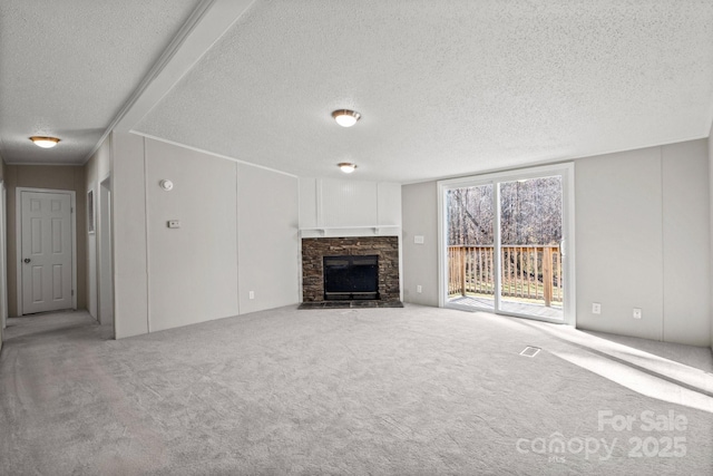 unfurnished living room featuring a stone fireplace, a textured ceiling, and carpet flooring