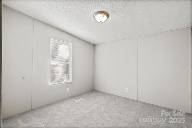 carpeted empty room featuring a textured ceiling