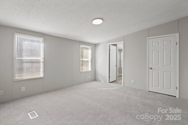 carpeted empty room featuring a textured ceiling