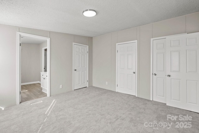 unfurnished bedroom featuring connected bathroom, a textured ceiling, and carpet flooring