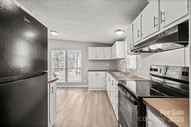 kitchen featuring electric range oven, white cabinetry, sink, black fridge, and light wood-type flooring