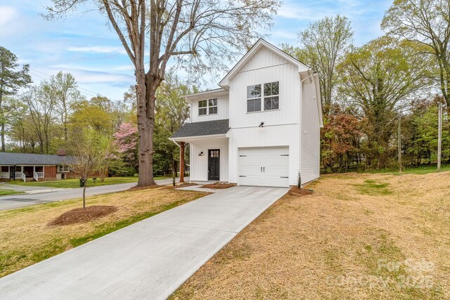modern farmhouse with a front yard, concrete driveway, and a garage