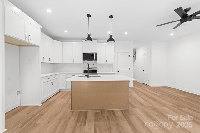 kitchen with a center island with sink, light countertops, a sink, and stainless steel appliances