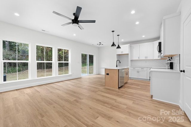 kitchen with light countertops, dishwasher, light wood-type flooring, open floor plan, and hanging light fixtures