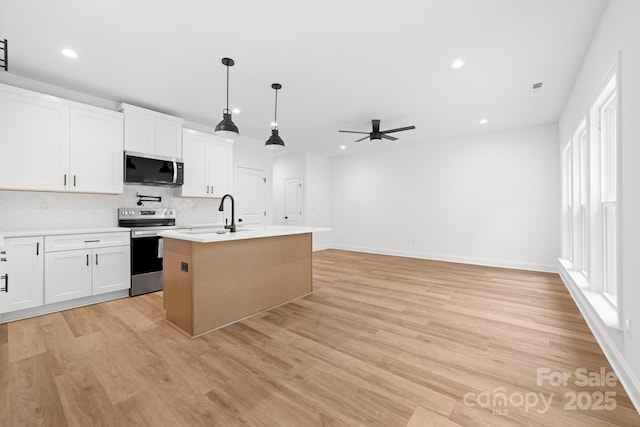 kitchen with light countertops, a sink, ceiling fan, light wood-style flooring, and appliances with stainless steel finishes