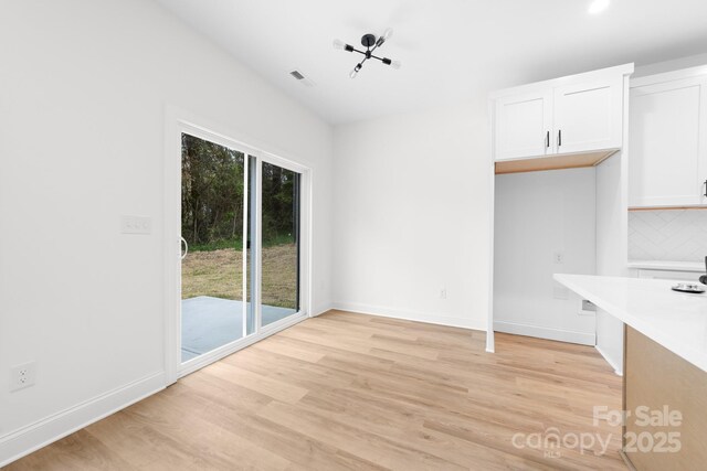 unfurnished dining area with baseboards, light wood-type flooring, and plenty of natural light