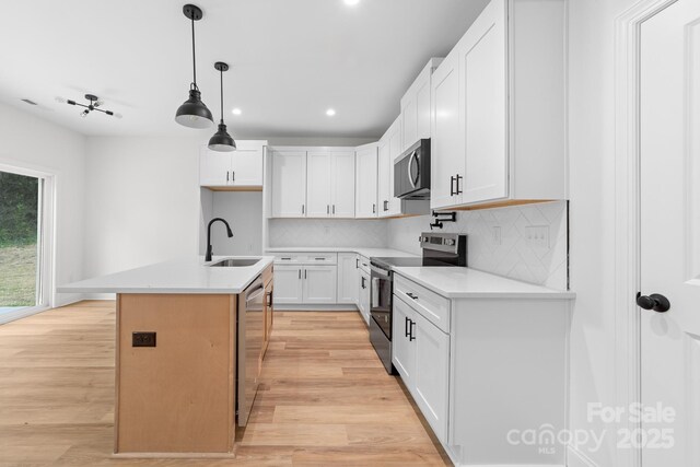 kitchen with backsplash, a sink, appliances with stainless steel finishes, and light wood-type flooring