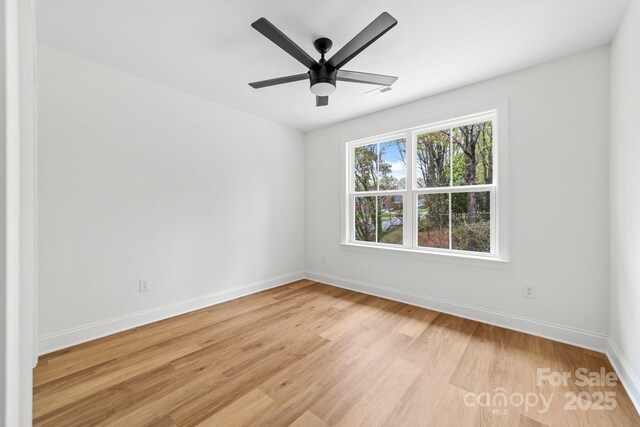 spare room featuring baseboards, visible vents, light wood-style flooring, and ceiling fan
