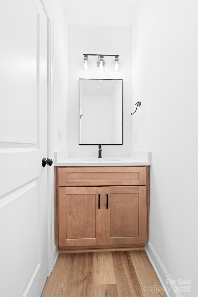bathroom with baseboards, wood finished floors, and vanity