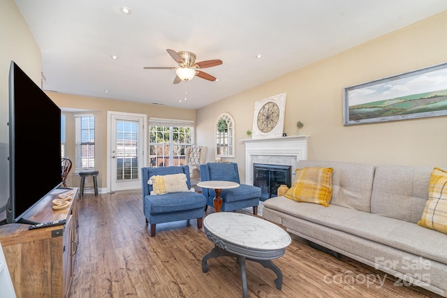 living room featuring ceiling fan, a high end fireplace, and hardwood / wood-style floors