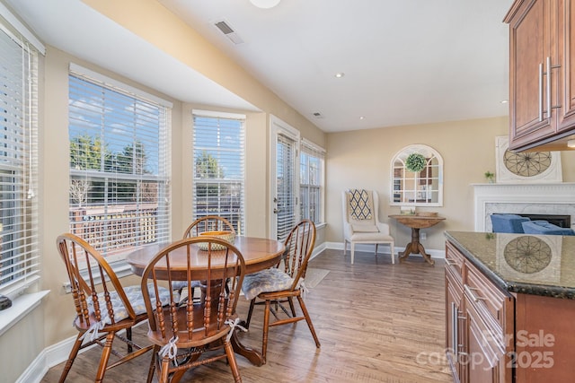 dining space featuring a premium fireplace and light hardwood / wood-style flooring