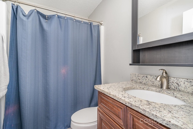 bathroom with vanity, toilet, and a textured ceiling