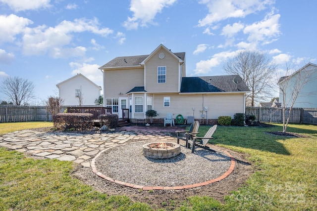 rear view of property featuring a fire pit, a lawn, a patio, and a deck