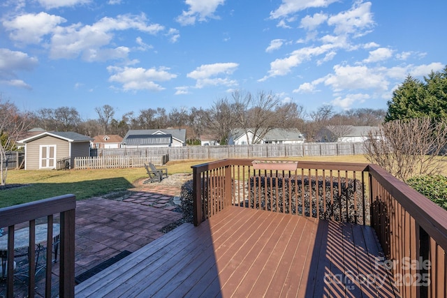 wooden deck with a shed, a lawn, and a patio