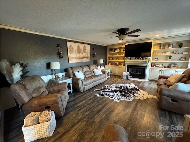 living room with a textured ceiling, ornamental molding, dark hardwood / wood-style flooring, built in features, and ceiling fan