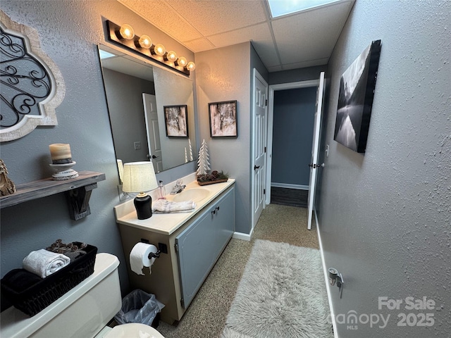 bathroom with a drop ceiling, vanity, and toilet