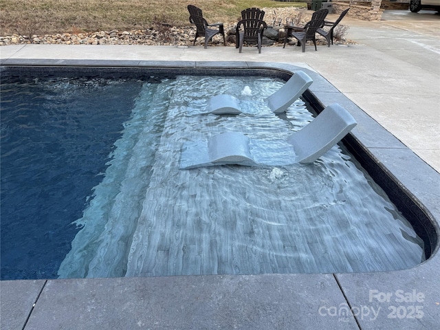 view of swimming pool with a fire pit and a patio area