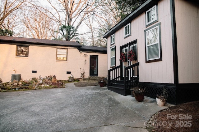 view of exterior entry with a patio area and central air condition unit