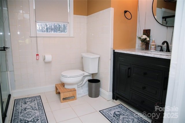 bathroom with tile patterned floors, toilet, tile walls, vanity, and a shower with door